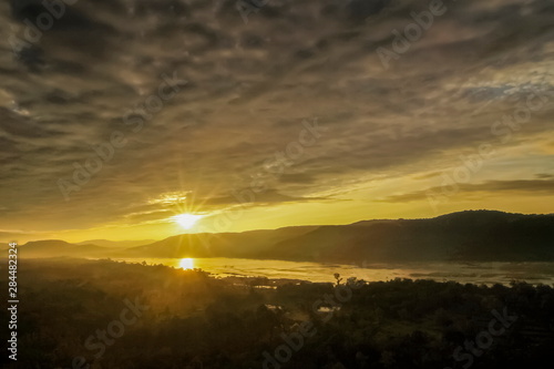 Mountain view morning above Mekong river around with the hills and yellow sun light in cloudy sky background, sunrise at Pha Taem View Point, Pha Taem National Park, Ubon Ratchathani, Thailand.
