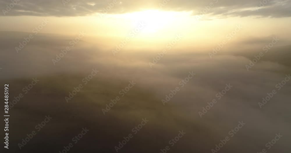 Aerial shot of flying towards rising sun in the foggy valley Aerial shot of flying towards rising sun in the foggy valley