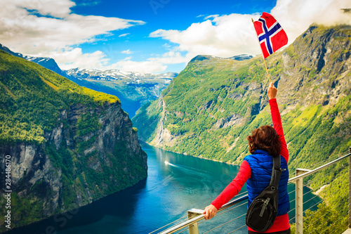 Tourist over Geirangerfjord with norwegian flag photo