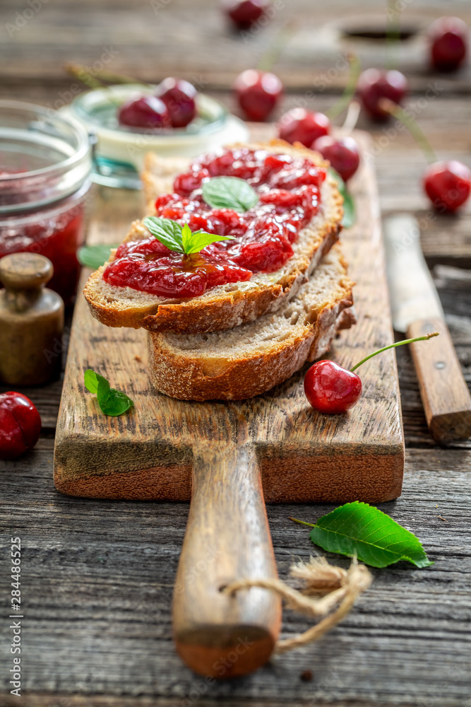 Tasty sandwich with jam made of cherries on wooden table