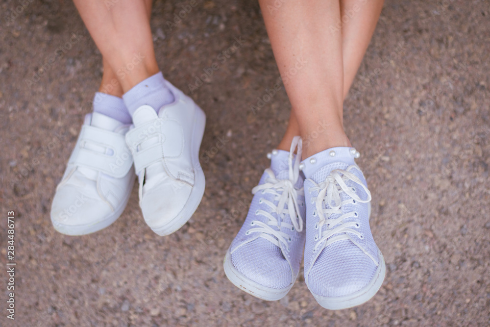 mother and daughter feet in white shoes