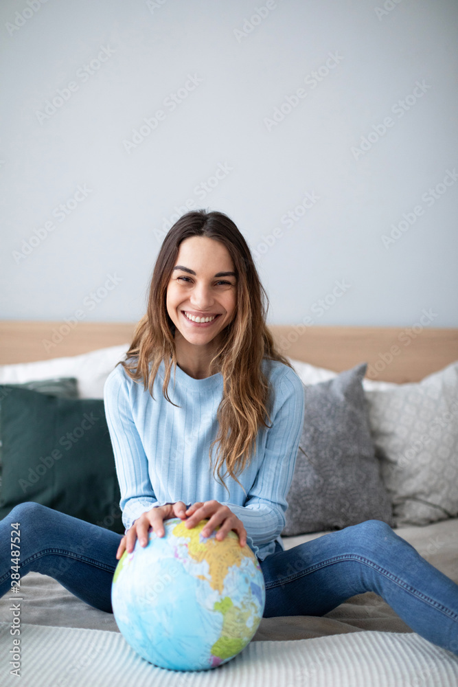 Joyful smiling woman indoors with a globe looking at the camera. Joyful smiling woman indoors with a globe looking at the camera.