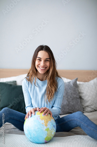 Joyful smiling woman indoors with a globe looking at the camera.