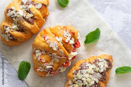 Tasty croissants covered jam and chocilate with cream and strawberry filling on grey cement background.Top view. photo