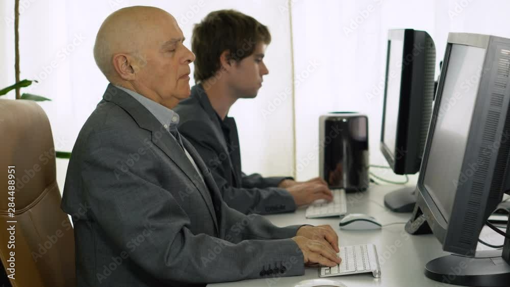 Old Businessman Stretching While Working on Computer in Office Old Businessman Stretching While Working on Computer in Office
