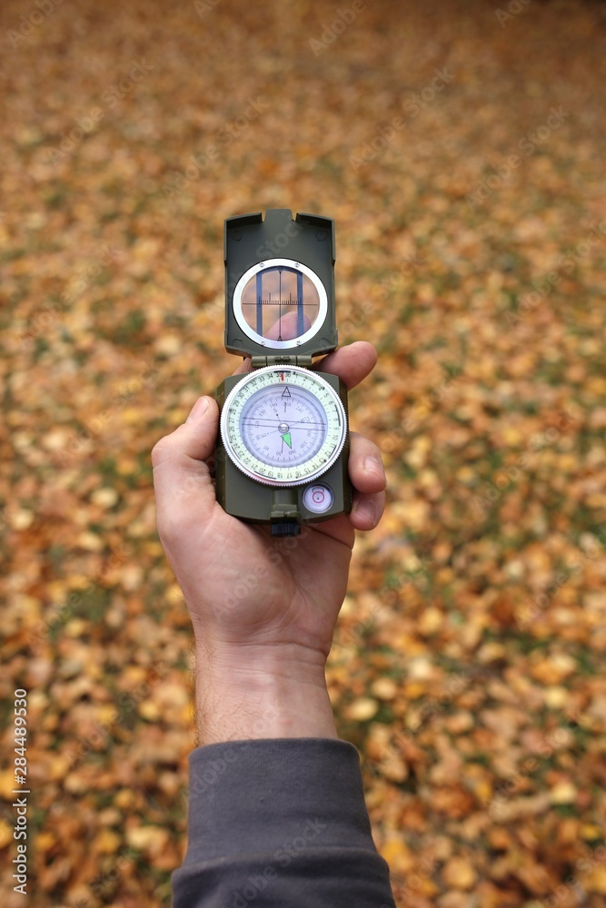 Naklejka premium Autumn concept. Autumn travel.Compass in a hand on a background of brown foliage