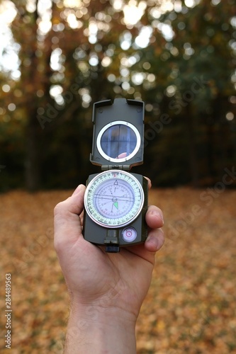 Autumn concept. Autumn travel.Compass in a male hand in the autumn forest.