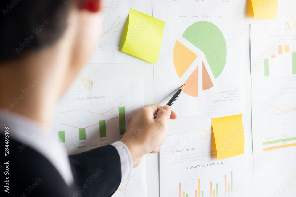 Asian young businessman using pen pointer analyzing financial documents on whiteboard for presentation Asian young businessman using pen pointer analyzing financial documents on whiteboard for presentation