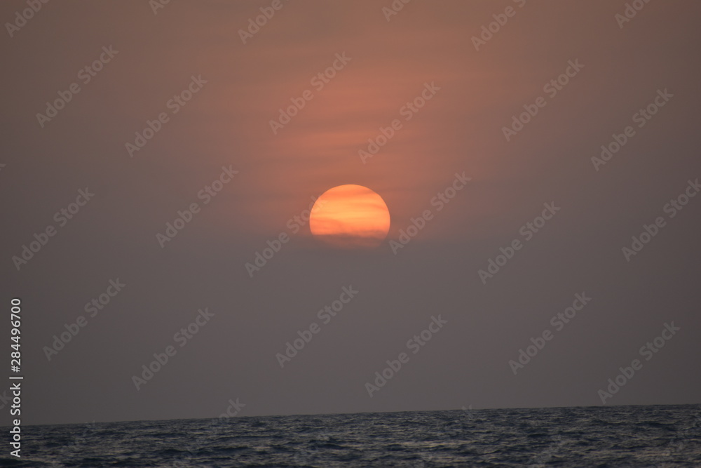 Scenic sunset seen from a beach with visible waves in the water at the bottom of the image Scenic sunset seen from a beach with visible waves in the water at the bottom of the image