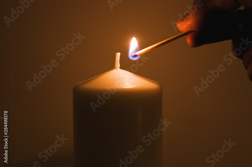 Lighting a candle with a burning match