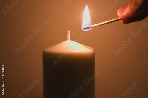 Bild auf Leinwand Lighting a candle with a burning match
