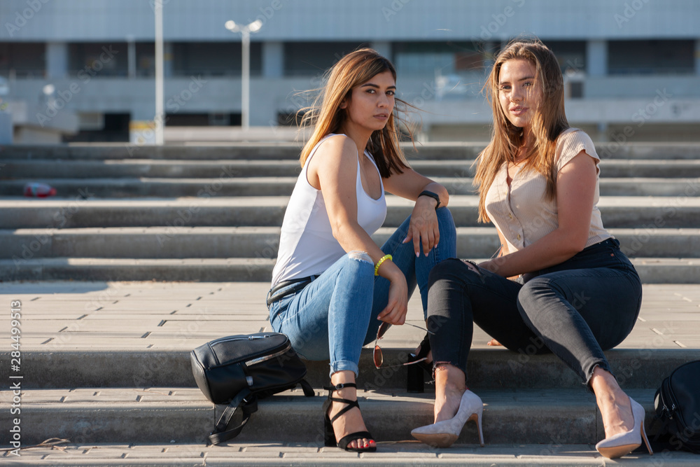 Obraz premium Beautiful girls in a city. Stylish ladies sitting on a stairs
