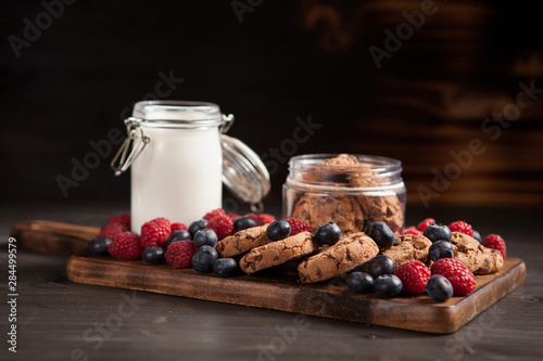 Delicious brown cookies on wooden plate with fresh bluebarries