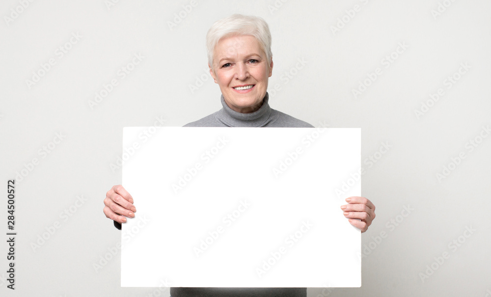 Beautiful aged woman posing with white empty board Beautiful aged woman posing with white empty board