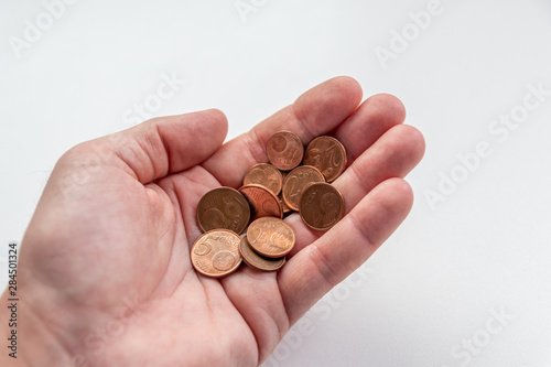 Männerhand eines Europäers hält EURO-Münzen zur Bezahlung mit Bargeld, Schuldenbegleichung oder zum Ausdruck von Armut und Reichtum