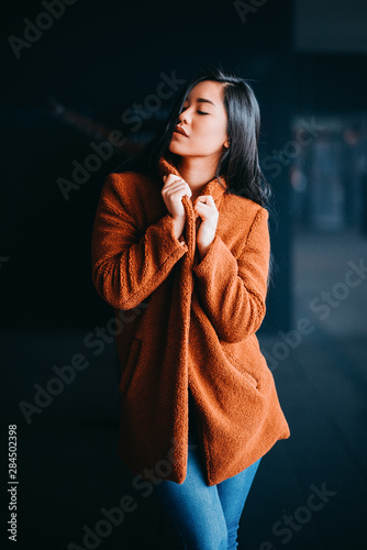 beautiful young serious asian woman with black hair and orange kashmere outdoor photo