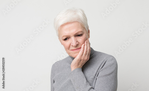 Elderly woman suffering from sudden tooth pain, panorama