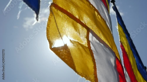 Buddhist prayer flags swaying in the wind in the rays of the rising sun in a temple. Closeup Slow Motion Footage. Shallow depth of field