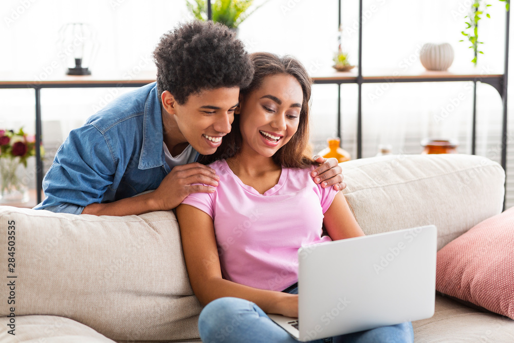 Young cheerful teens browsing video on laptop at home Young cheerful teens browsing video on laptop at home