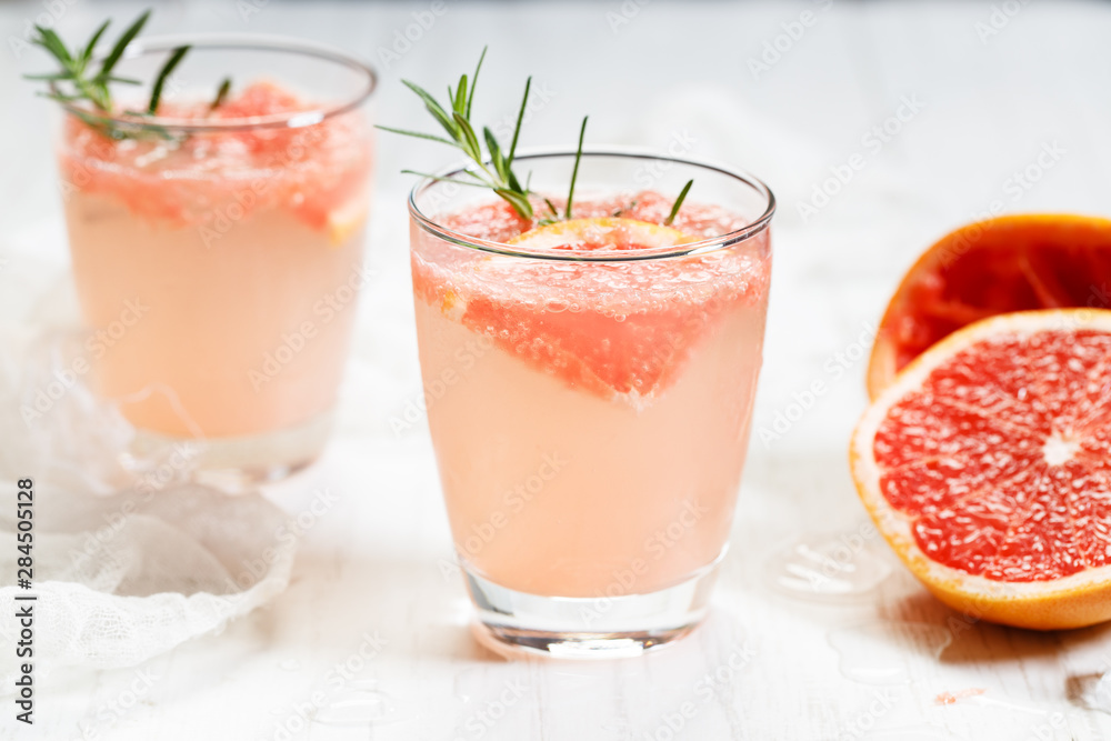 Glass of grapefruit drink with ice and rosemary Glass of grapefruit drink with ice and rosemary
