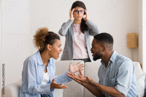 Confused Marital Psychologist Witnessing Afro Couple Arguing In Office