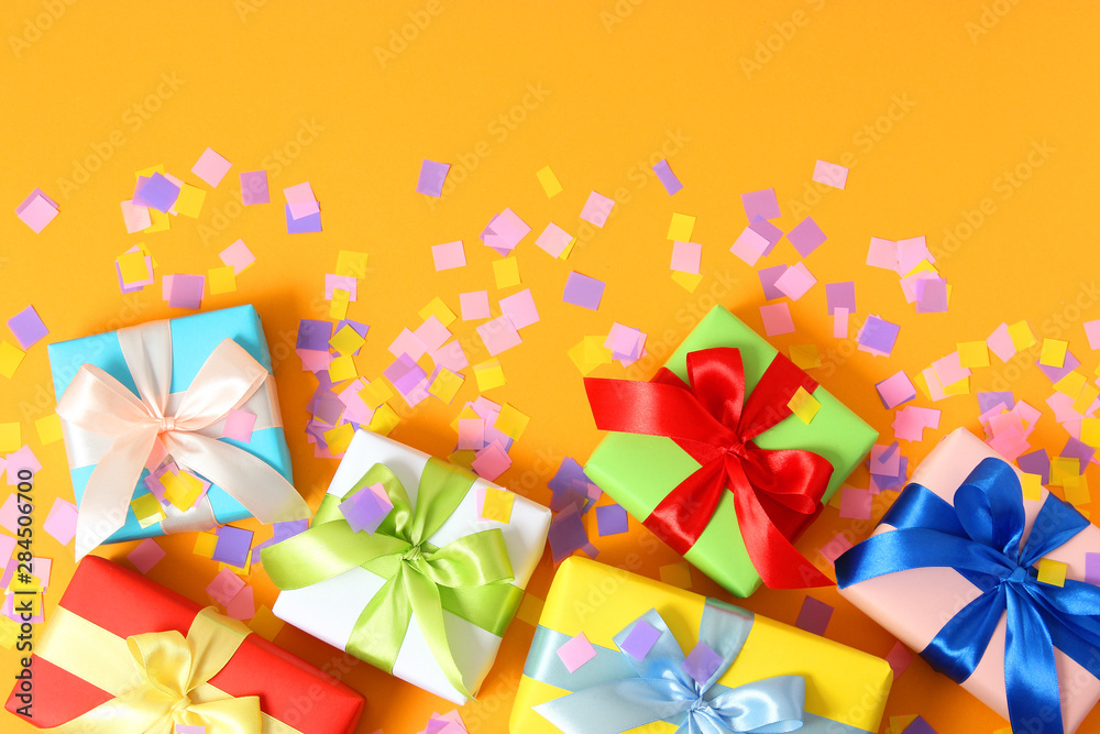 gifts and confetti on a colored background top view. Holiday giving gifts