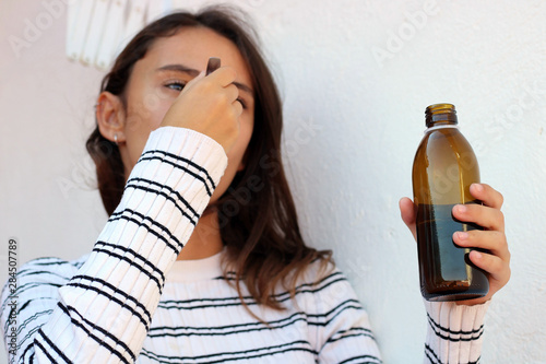 Health and medicine - Young woman taking a cough syrup on a white background.