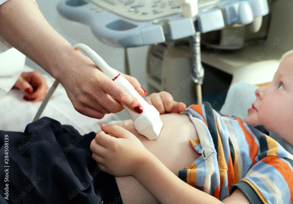 An ultrasound doctor makes an ultrasound of the abdominal cavity of the child. The boy is being