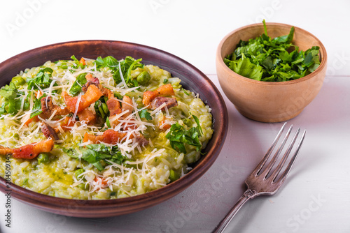 Classic Italian risotto with peas and fried bacon on a clay rustic plate