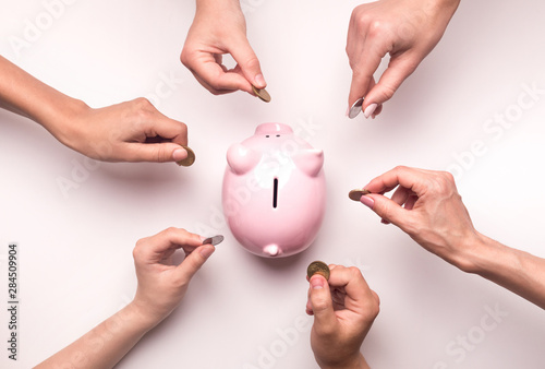 People hands throwing coins in piggy bank for crowdfunding photo