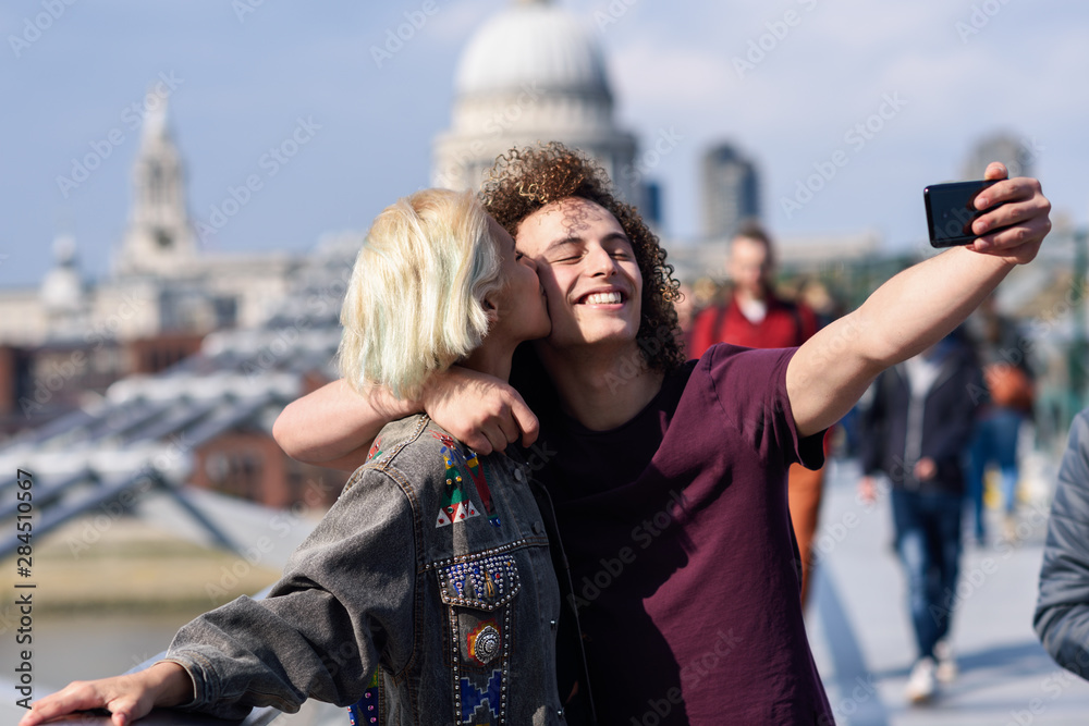 Happy couple taking a selfie photograph on London's Millennium Bridge