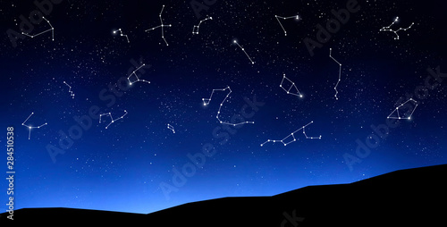 Zodiac signs on clear night sky above mountains