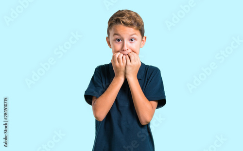 Little boy is a little bit nervous and scared on blue background