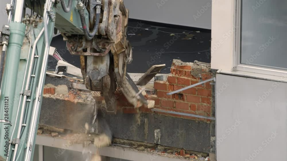 Demolition machine tearing down a wall of a condemned building.