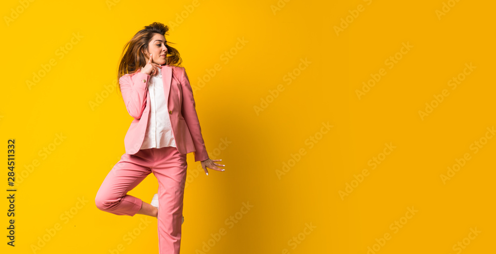 Young woman jumping over isolated yellow wall - obrazy, fototapety, plakaty 