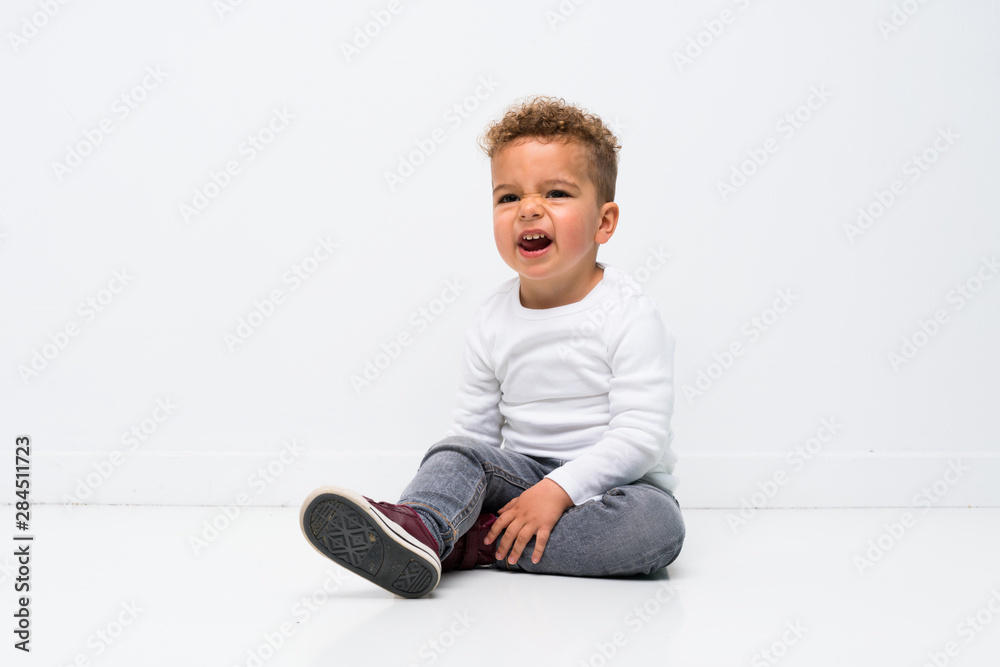 kid over isolated white background sitting on the floor kid over isolated white background sitting on the floor