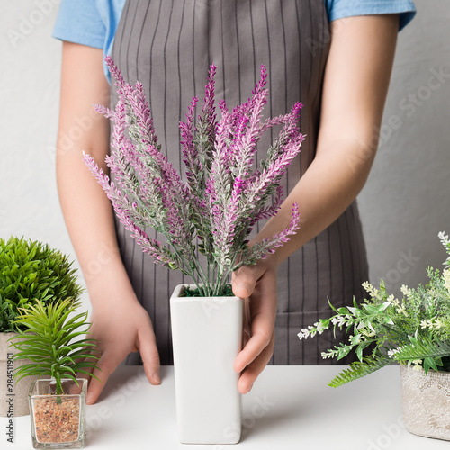 Woman putting lavender plant on table, crop
