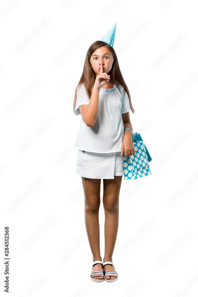 A full-length shot of a Little girl at a birthday party holding a gift bag showing a sign of closing mouth and silence gesture on isolated white background A full-length shot of a Little girl at a birthday party holding a gift bag showing a sign of closing mouth and silence gesture on isolated white background