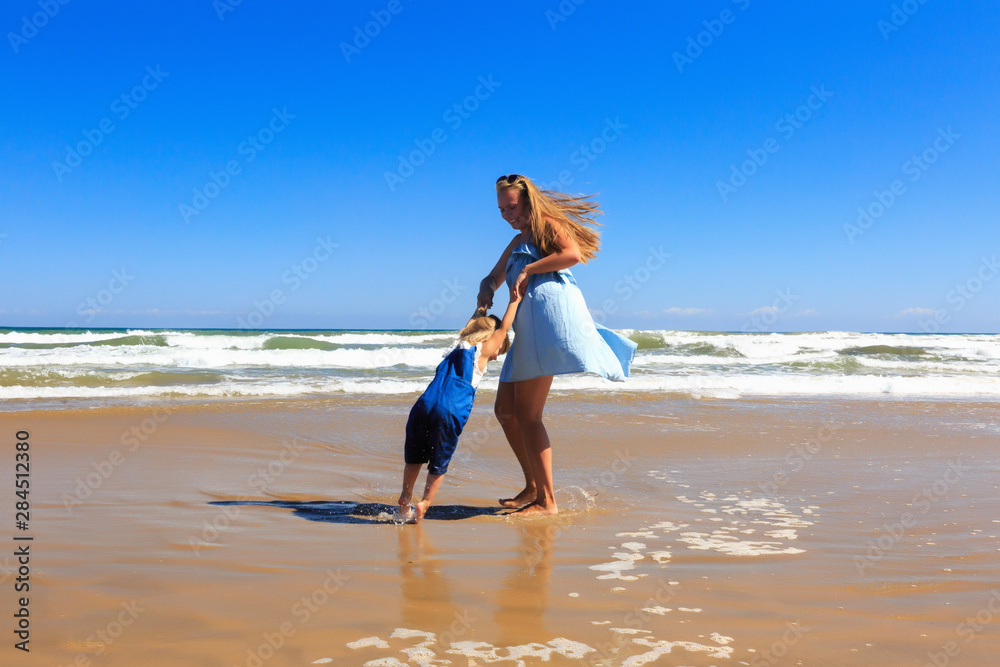 Naklejka premium Mother and daughter are spinning on the beach at sunny day.
