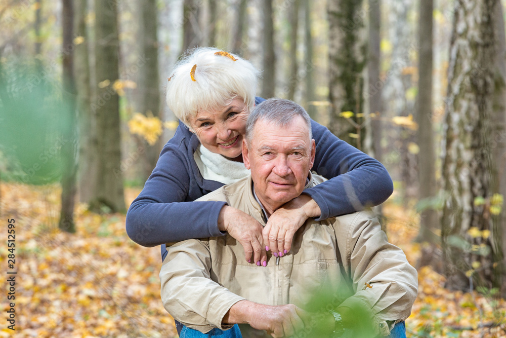 Happy senior couple sitting and smiling in an autumn park