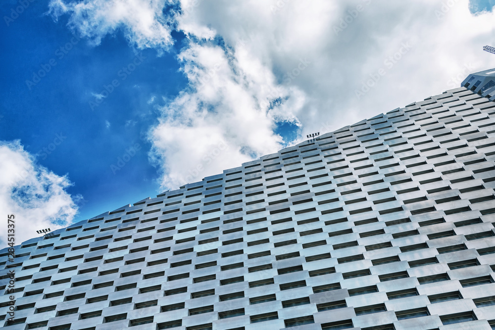 Facade of a modern metal building against a cloudy sky. Bottom view Architecture Facade of a modern metal building against a cloudy sky. Bottom view Architecture
