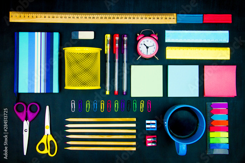 Vászonkép Colorful office supplies neatly geometrically evenly laid out on blackboard background