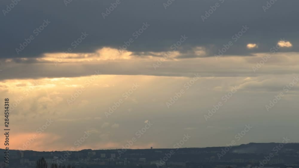 Timelapse of the setting sun behind the clouds at sunset over the small town. Swirling clouds before sunset. Low key Timelapse of the setting sun behind the clouds at sunset over the small town. Swirling clouds before sunset. Low key