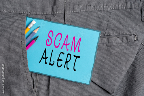 Conceptual hand writing showing Scam Alert. Concept meaning unsolicited email that claims the prospect of a bargain Writing equipment and blue note paper in pocket of trousers