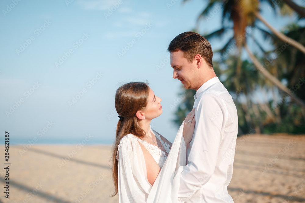 Fototapeta premium Beautiful wedding couple bride and groom at wedding day outdoors at ocean beach. Happy marriage couple outdoors on nature, soft sunny lights. Loving man and woman at marriage day