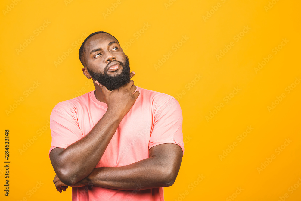 Thinking black Afro American man with serious expression looking, posing isolated against yellow background. Thinking black Afro American man with serious expression looking, posing isolated against yellow background.