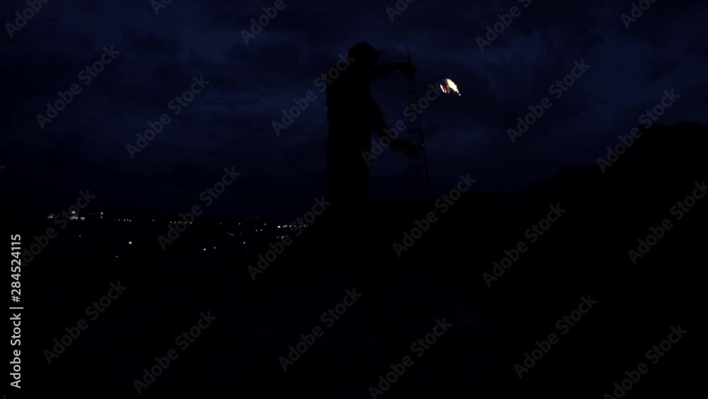 Male Fire Show Performance with burning rope dart, night city lights on dark background. Young man dancing with fireball. Caucasian bearded guy performed dances. Modern improvisation art. Male Fire Show Performance with burning rope dart, night city lights on dark background. Young man dancing with fireball. Caucasian bearded guy performed dances. Modern improvisation art.