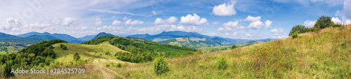 wonderful autumn mountain panorama. pikui peak of watershed ridge beneath clouds. trees on grassy rolling hills. wonderful carpathian countryside on a sunny day of september.