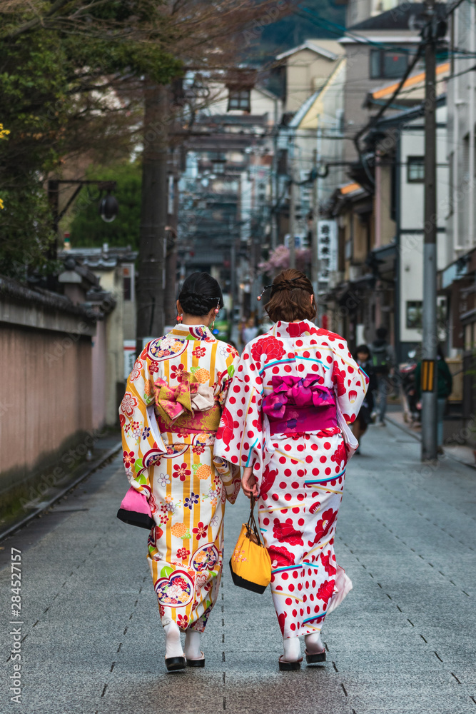 Two young Japanese girls wearing traditional Japanese clothes called yukata in old streets of Gion, Kyoto