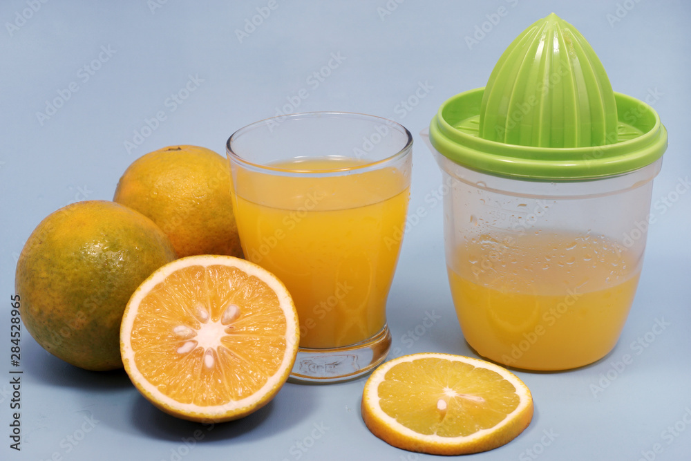 a glass of sweet orange juice with orange slices and squeezer isolated on blue a glass of sweet orange juice with orange slices and squeezer isolated on blue